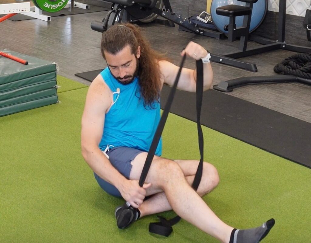 Dr. John attaching the strap to his right foot to help him with his first javelin mobility exercise